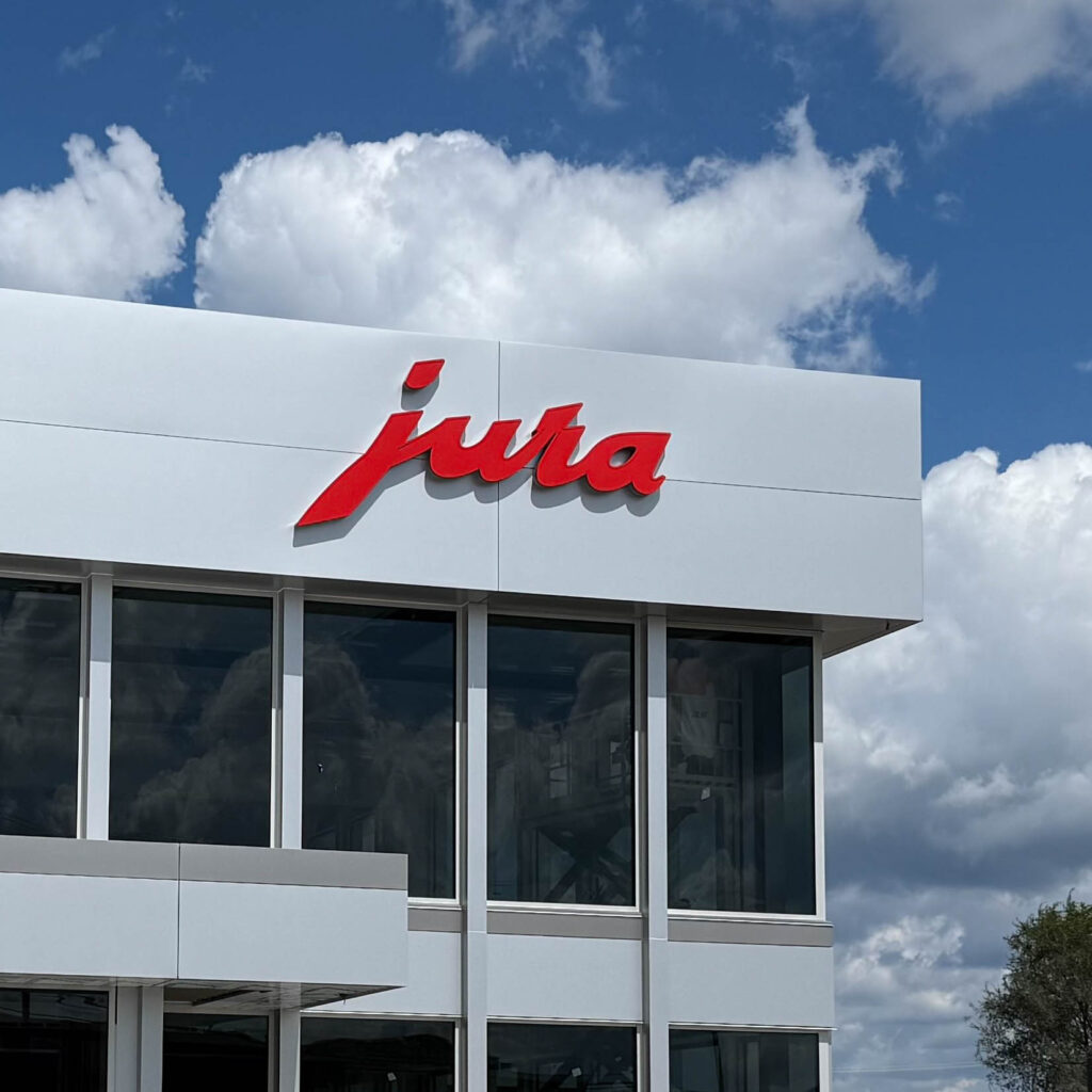 JURA sign on side of building against cloudy sky